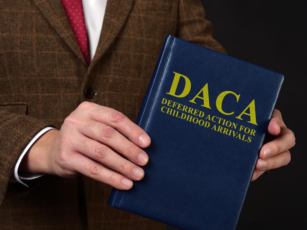 Man in suit shows the book Deferred Action for Childhood Arrivals DACA