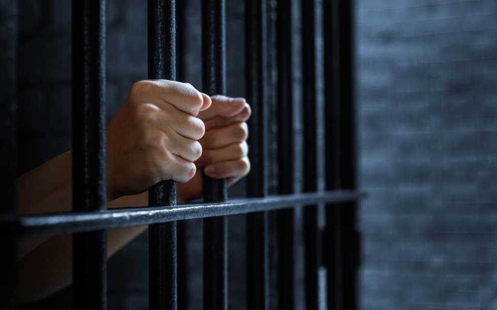 Women's hands holding prison railings